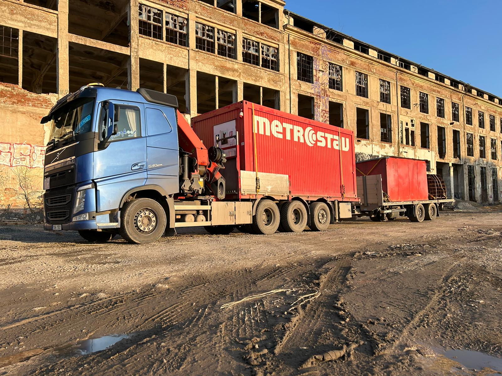 Nákladní vozidlo s hydraulickou rukou při skládání materiálu